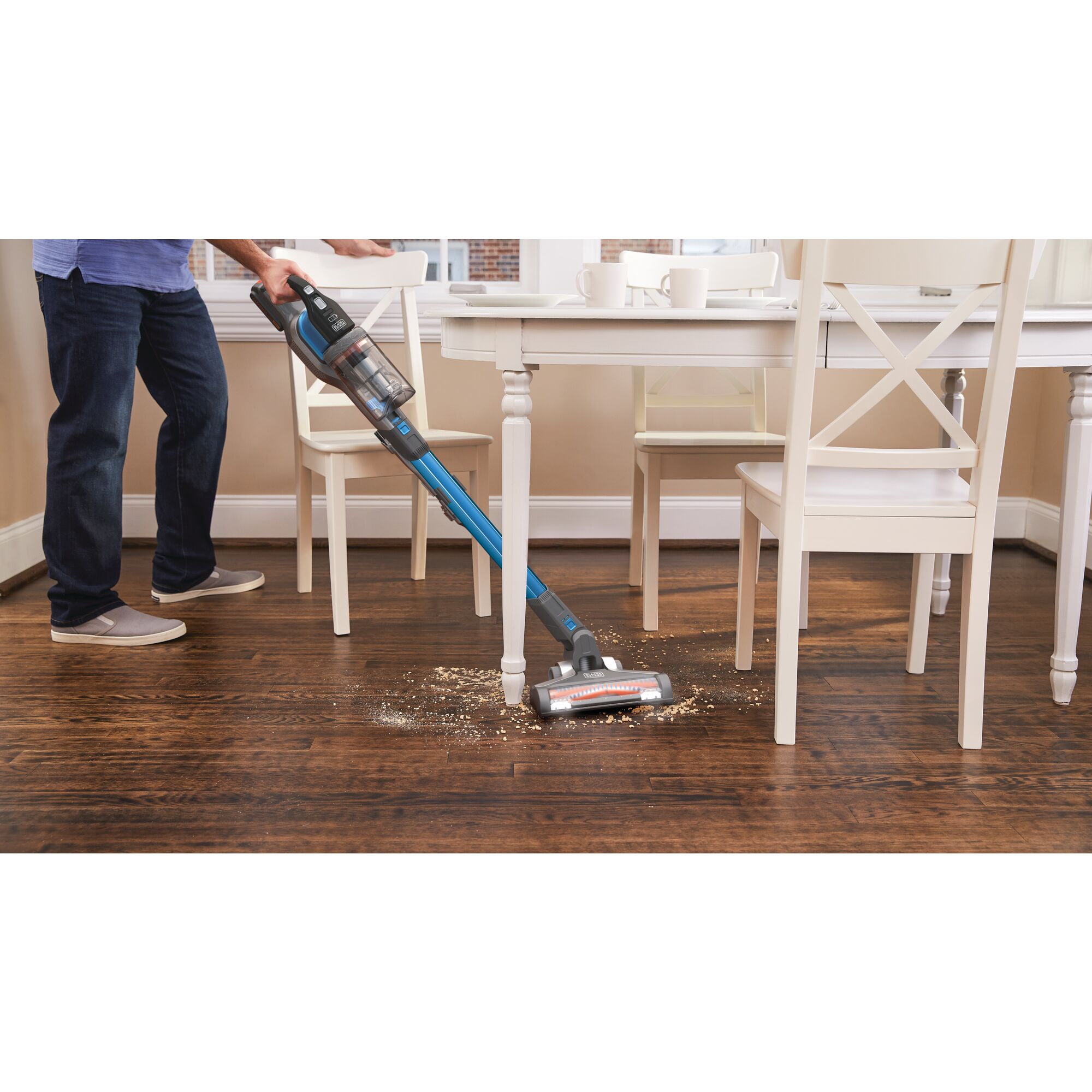 POWER SERIES Extreme Cordless Stick Vacuum Cleaner being used for cleaning mess under dining table.