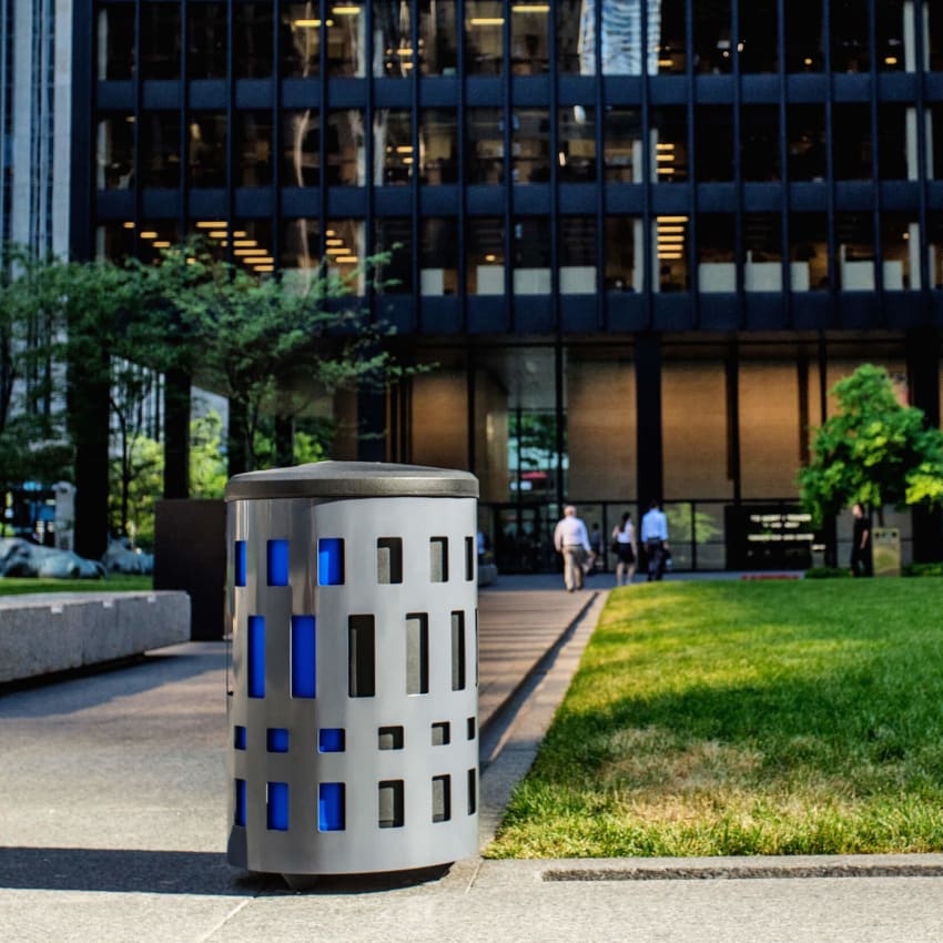 triple recycling and trash container made from durable powder coated steel with plastic lid and color-coded liners streetside on a city sidewalk
