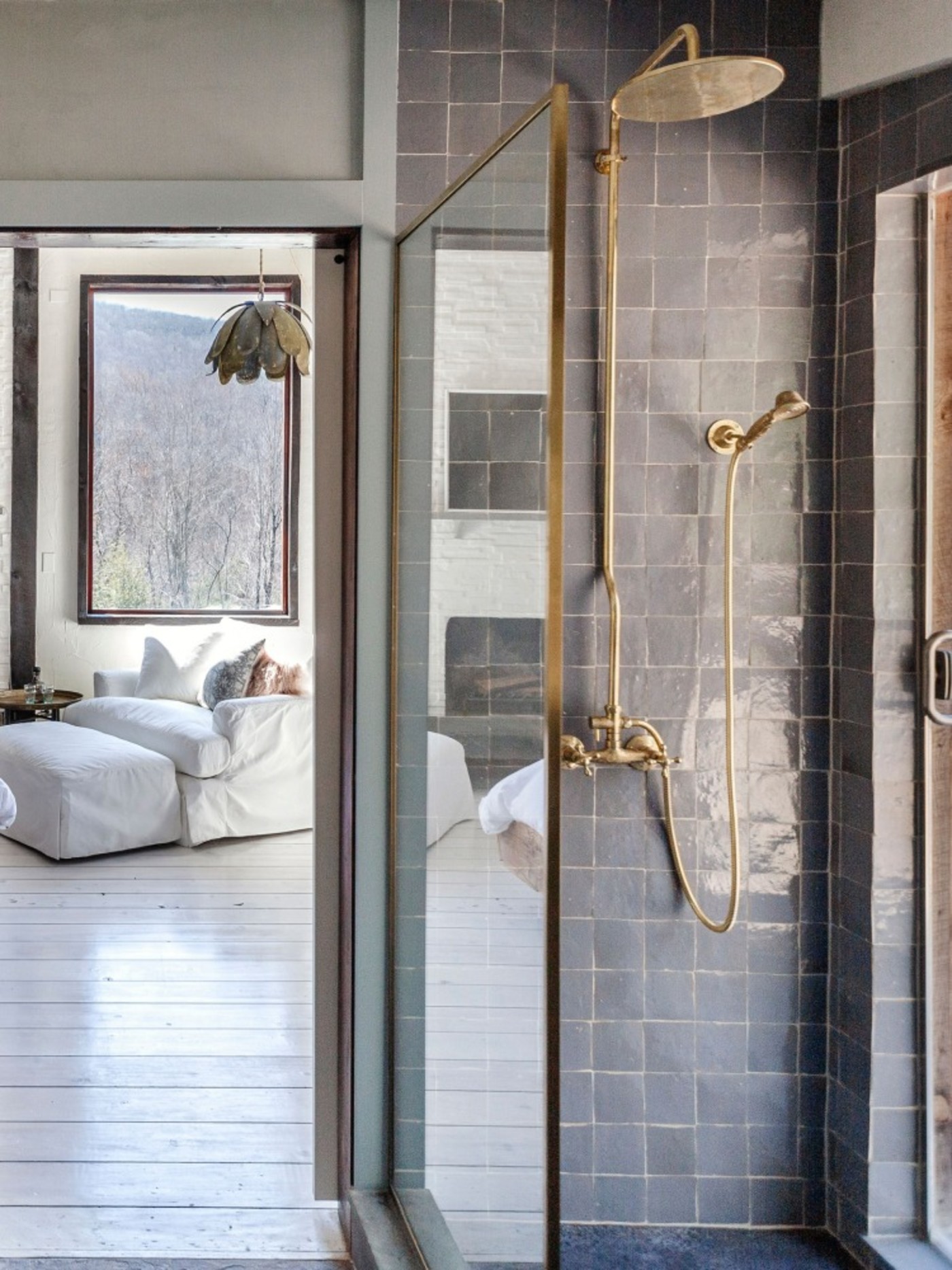 a bathroom with a tiled shower. and a doorway looking into a bedroom