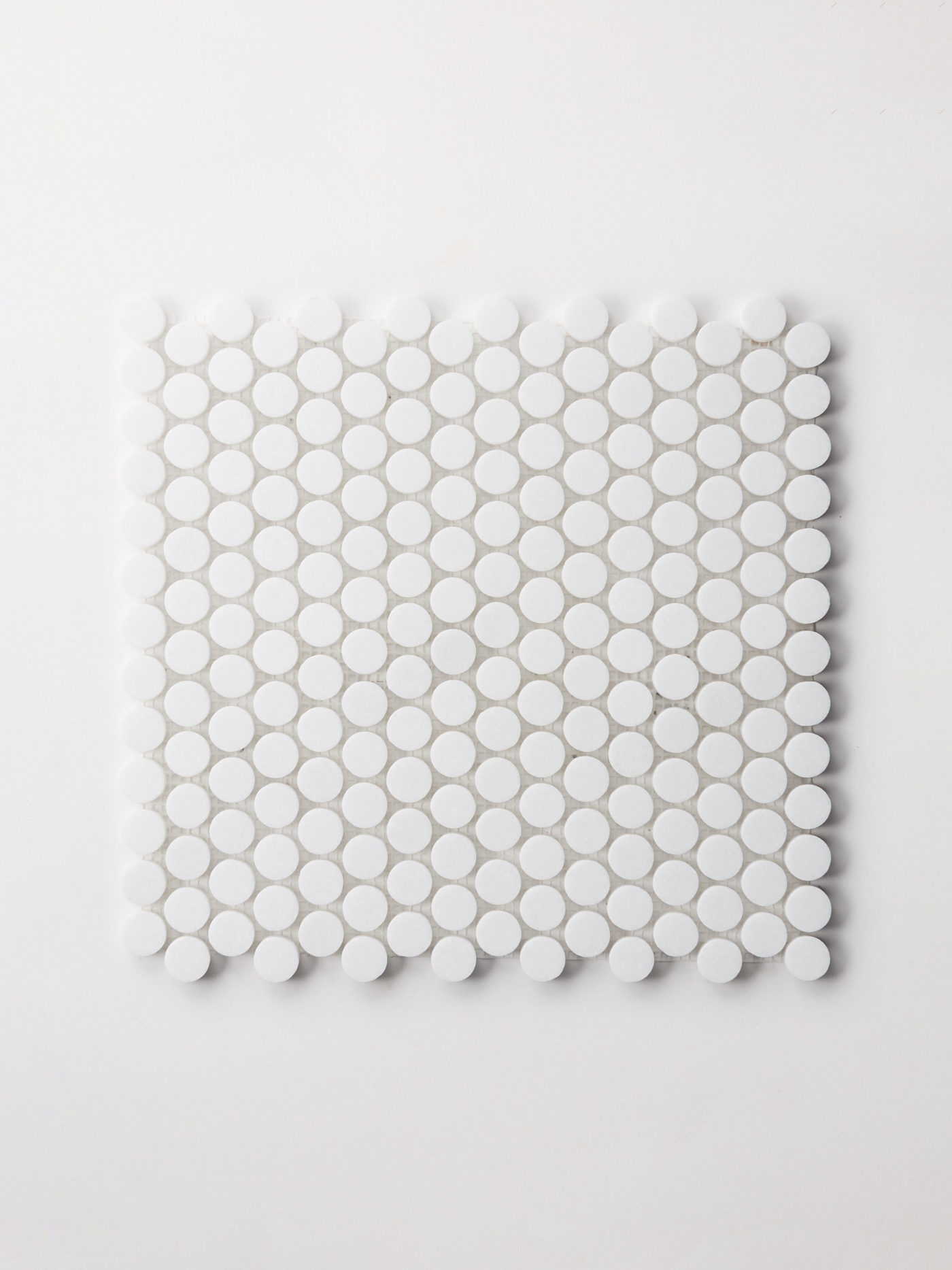 a sheet of small white penny shaped tiles on a white background.