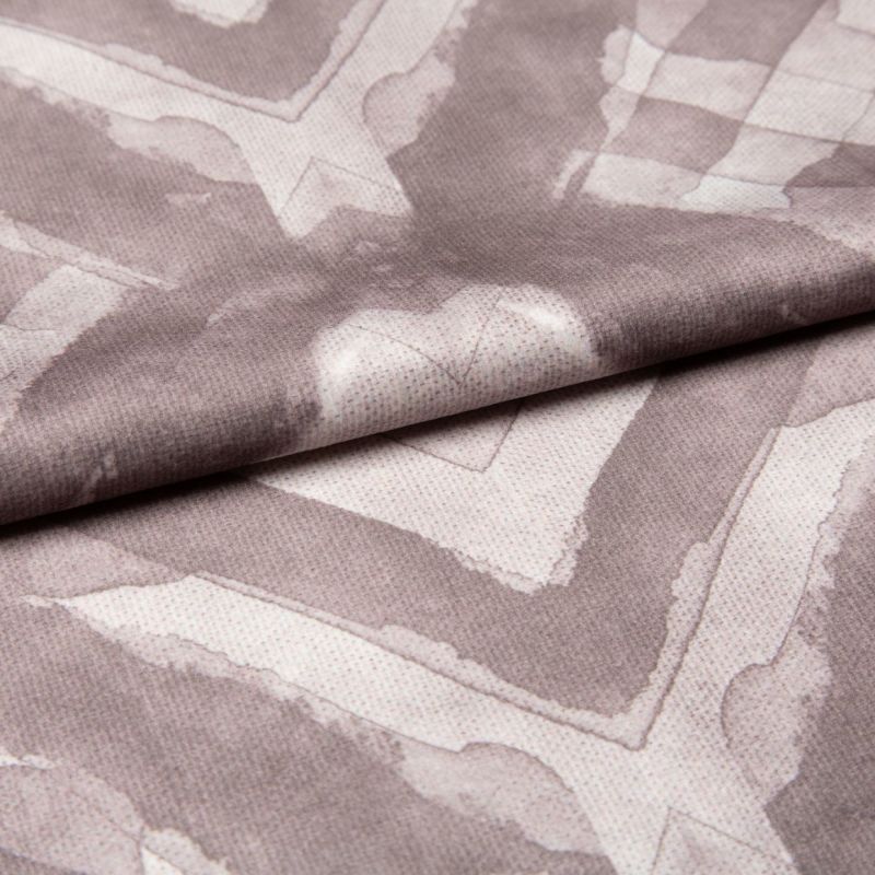 Soft woven fabric with faded mauve geometric frames and subtle heart motif (folded across the center), draped and overlapped to reveal stitched texture, close-up under even studio lighting.