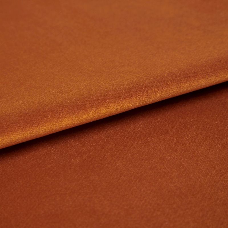 Copper-orange satin fabric, folded with visible edge, reflecting light â€” close-up studio shot showing soft sheen, fine texture, and warm even lighting.