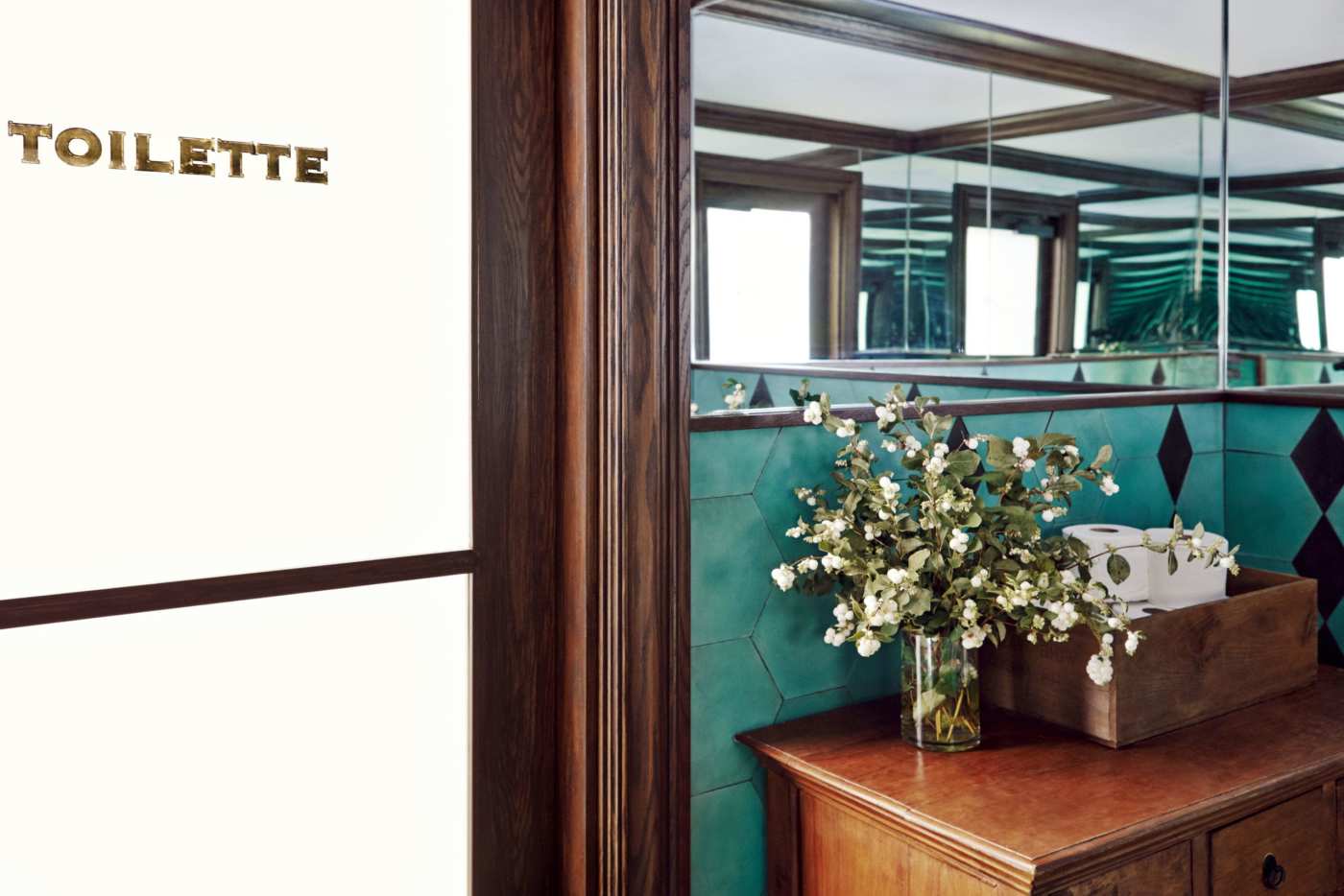 a bathroom with a mirror and green tiled walls.