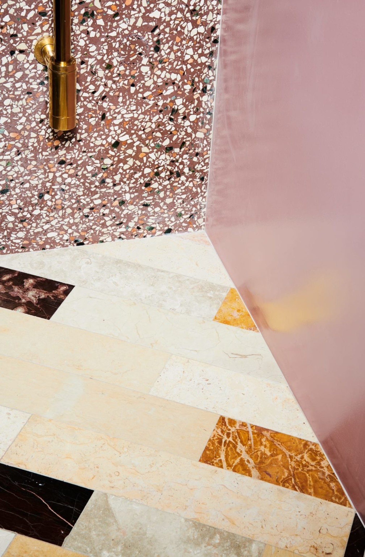 a bathroom with a marble tile floor and terracotta tile wall.