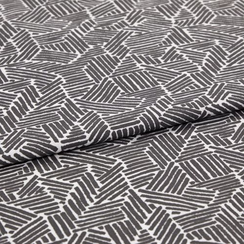 Folded patterned fabric: gray-and-white geometric print of short parallel stripes forming irregular polygons, folded across the middle. Close-up on flat surface with even studio lighting.