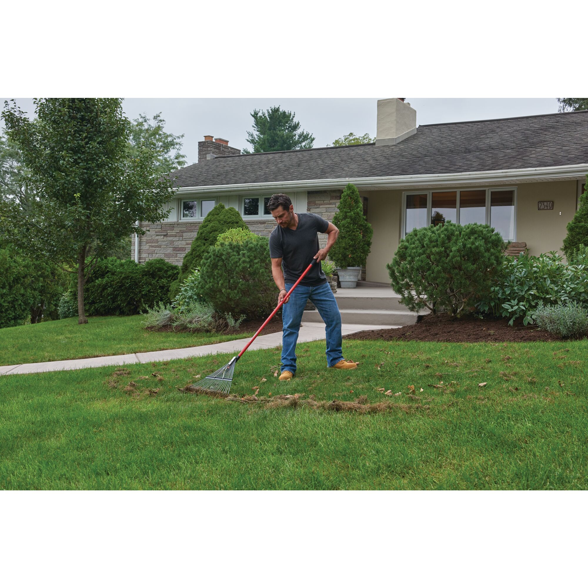 24 inch tine fiberglass handle lawn rake being used by a person.