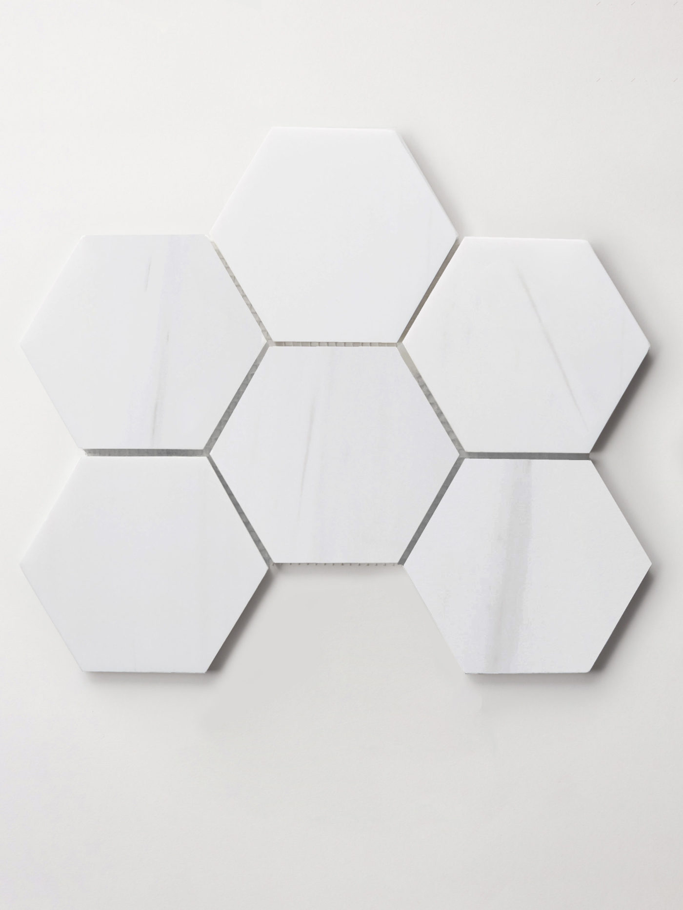 a sheet of six white hexagon tile on a white surface.