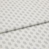 Light-coloured cotton fabric with repeating small grey leaf motifs, folded across the middle, shown in a soft, evenly lit studio close-up.