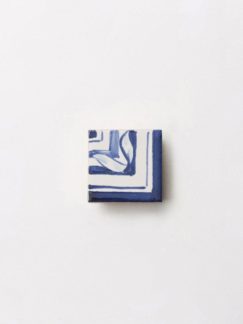a blue and white hand painted tile on a white surface.