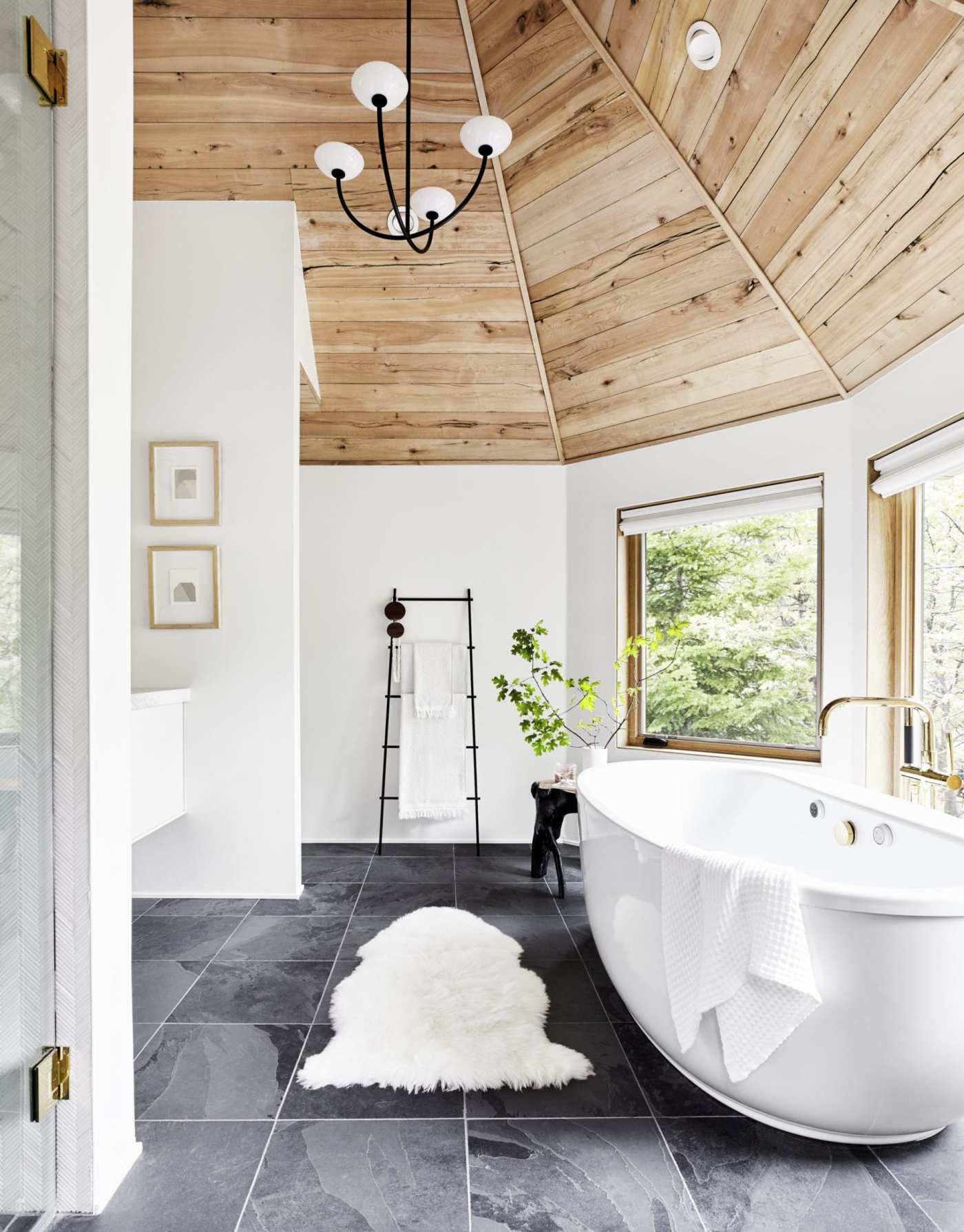 a bathroom with a wooden ceiling, white tub, and slate tile floor.