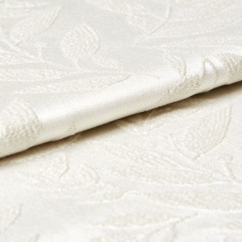 Cream damask fabric with raised floral pattern and satin sheen, shown folded and slightly overlapping; close-up view revealing textured embroidery and soft, diffuse lighting on a neutral surface.