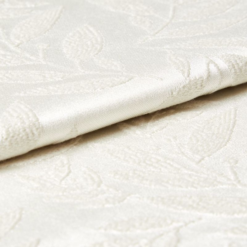Cream damask fabric with raised floral pattern and satin sheen, shown folded and slightly overlapping; close-up view revealing textured embroidery and soft, diffuse lighting on a neutral surface.