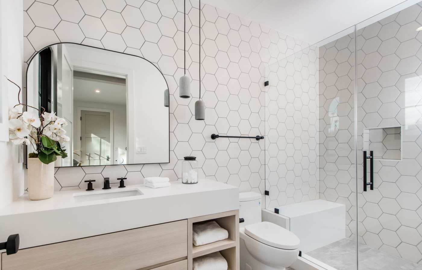 a bathroom with white hexagon tile and a glass shower.