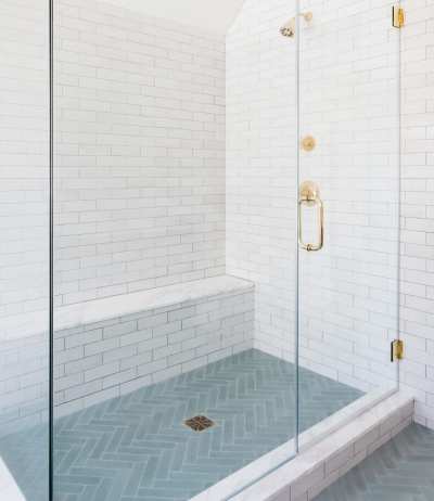 a bathroom with a glass shower stall and white tile.