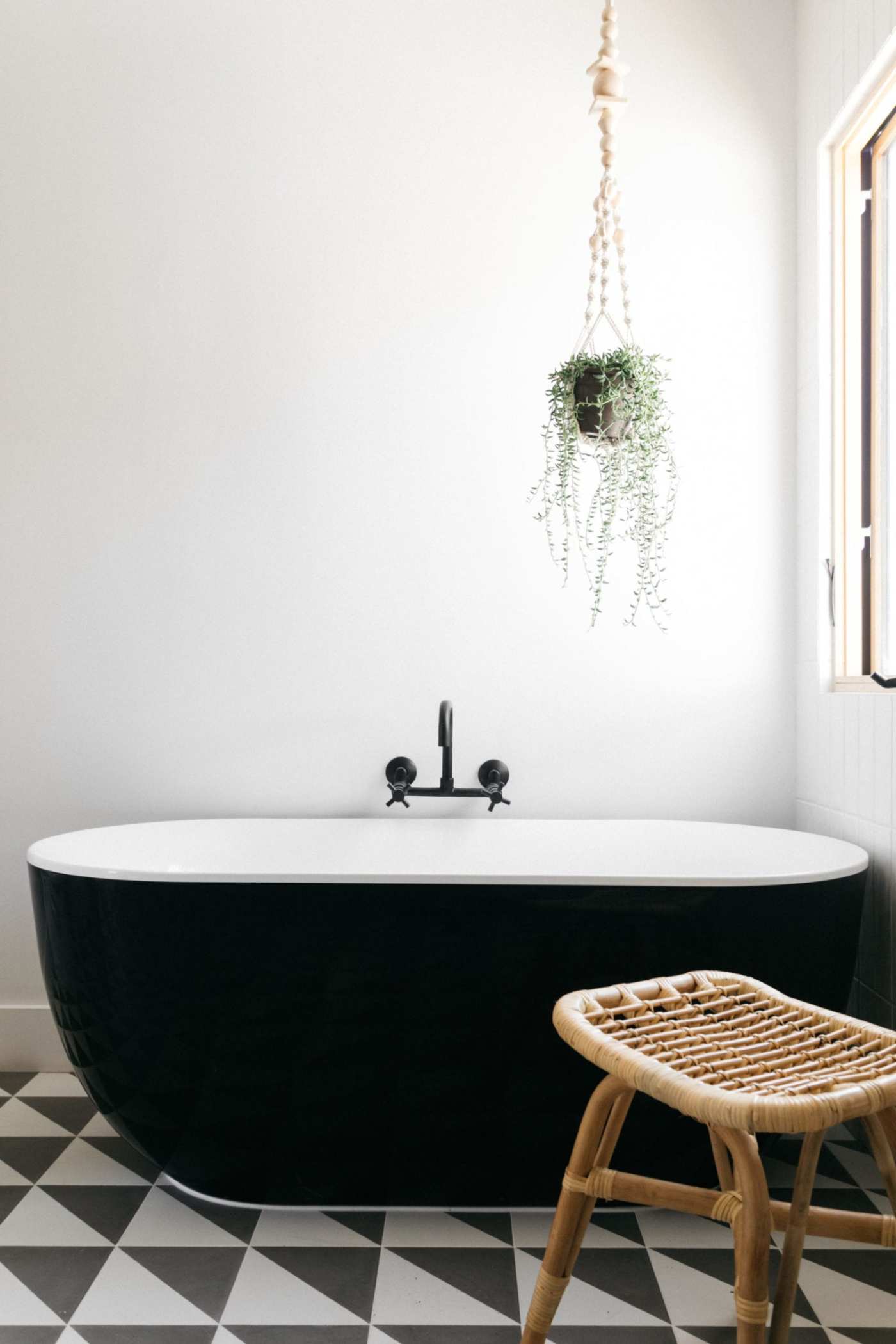 a black and white bathroom with a wooden chair and tiled floor.