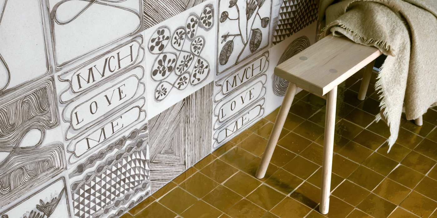 a wooden stool in front of a tiled wall.