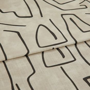 Beige linen-like curtain fabric with bold black abstract line pattern, hem visible; folded into a horizontal pleat; close-up in soft, neutral lighting showing fabric texture.