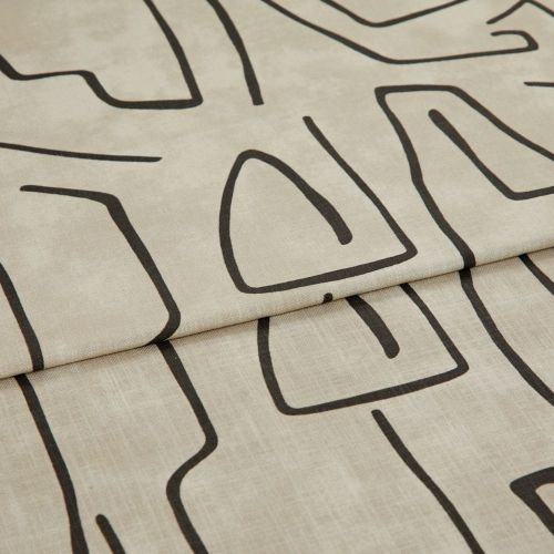 Beige linen-like curtain fabric with bold black abstract line pattern, hem visible; folded into a horizontal pleat; close-up in soft, neutral lighting showing fabric texture.