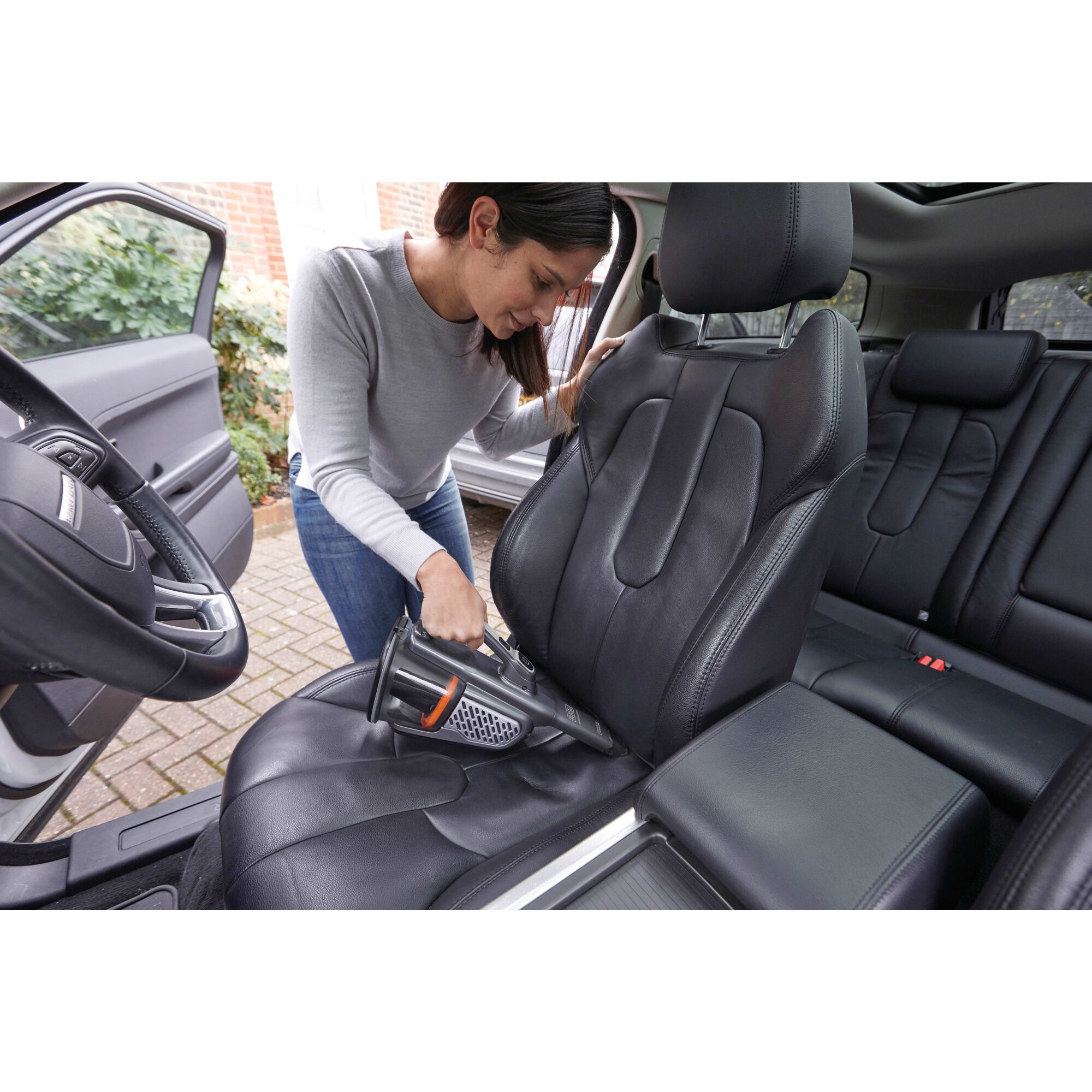 16 volt max dustbuster advanced clean plus hand vacuum being used to vacuum a car seat by a person.