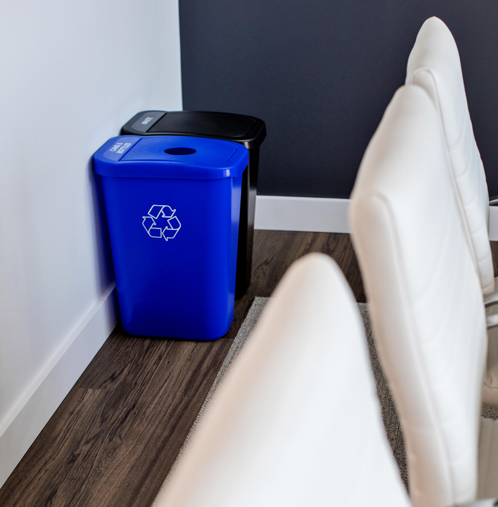 color-coded blue and black office recycling and waste containers in a corporate office space