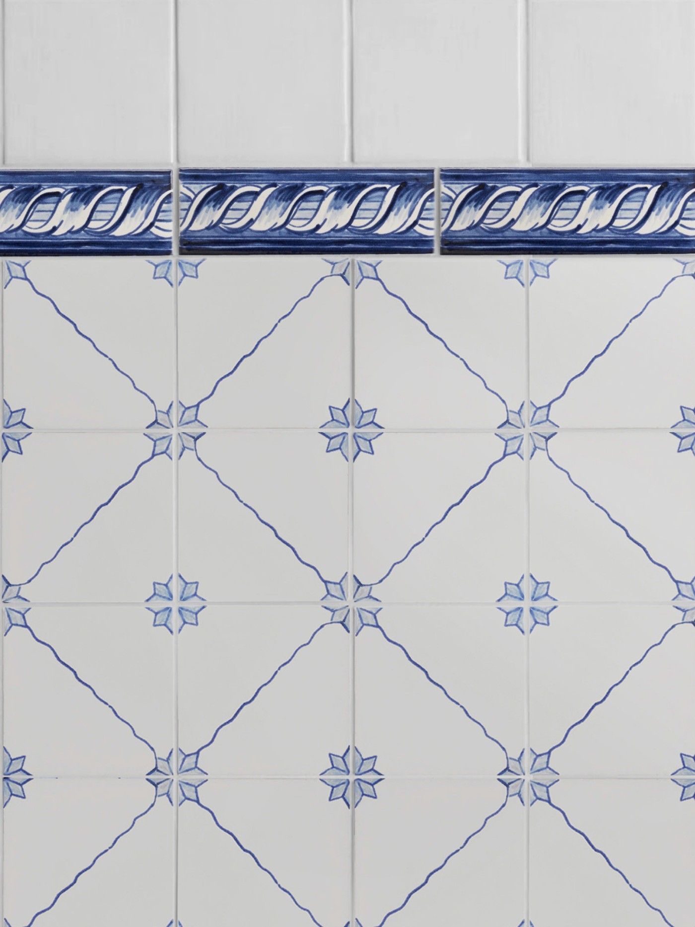 a blue and white tiled wall with a decorative border.