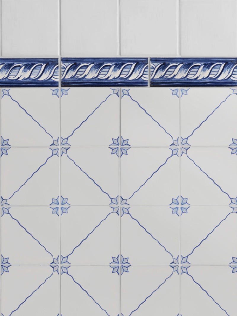 a blue and white tiled wall with a decorative border.