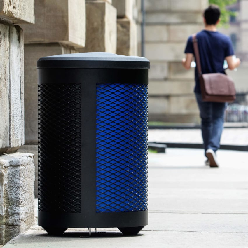 black metal outdoor waste and recyclables container with a plastic canopy lid on a city sidewalk with people walking by