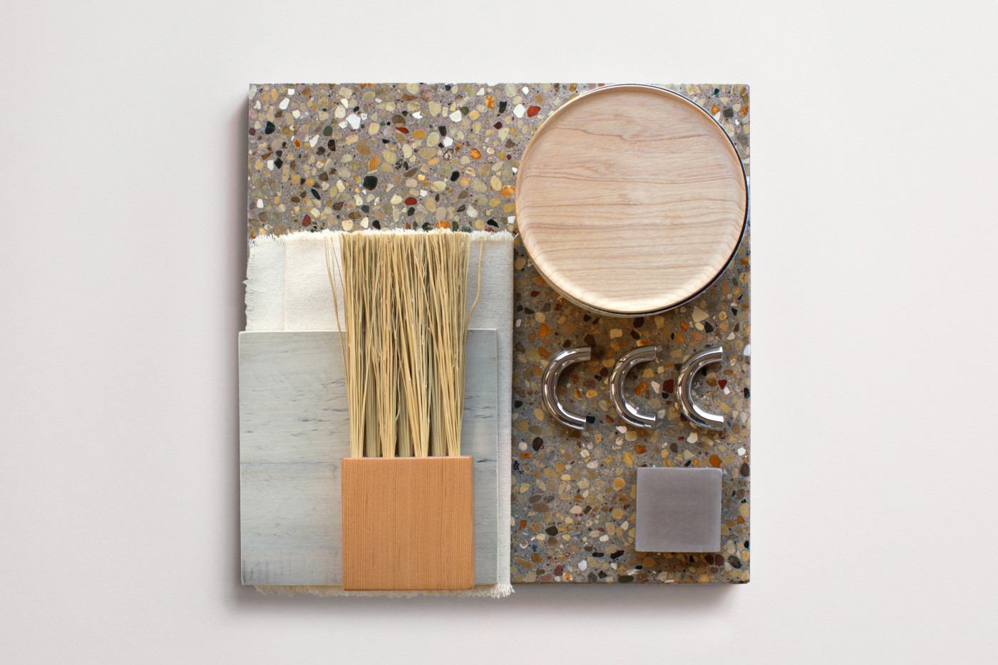 a grey terrazzo tile with a brush, a wooden circle, and other items on it.