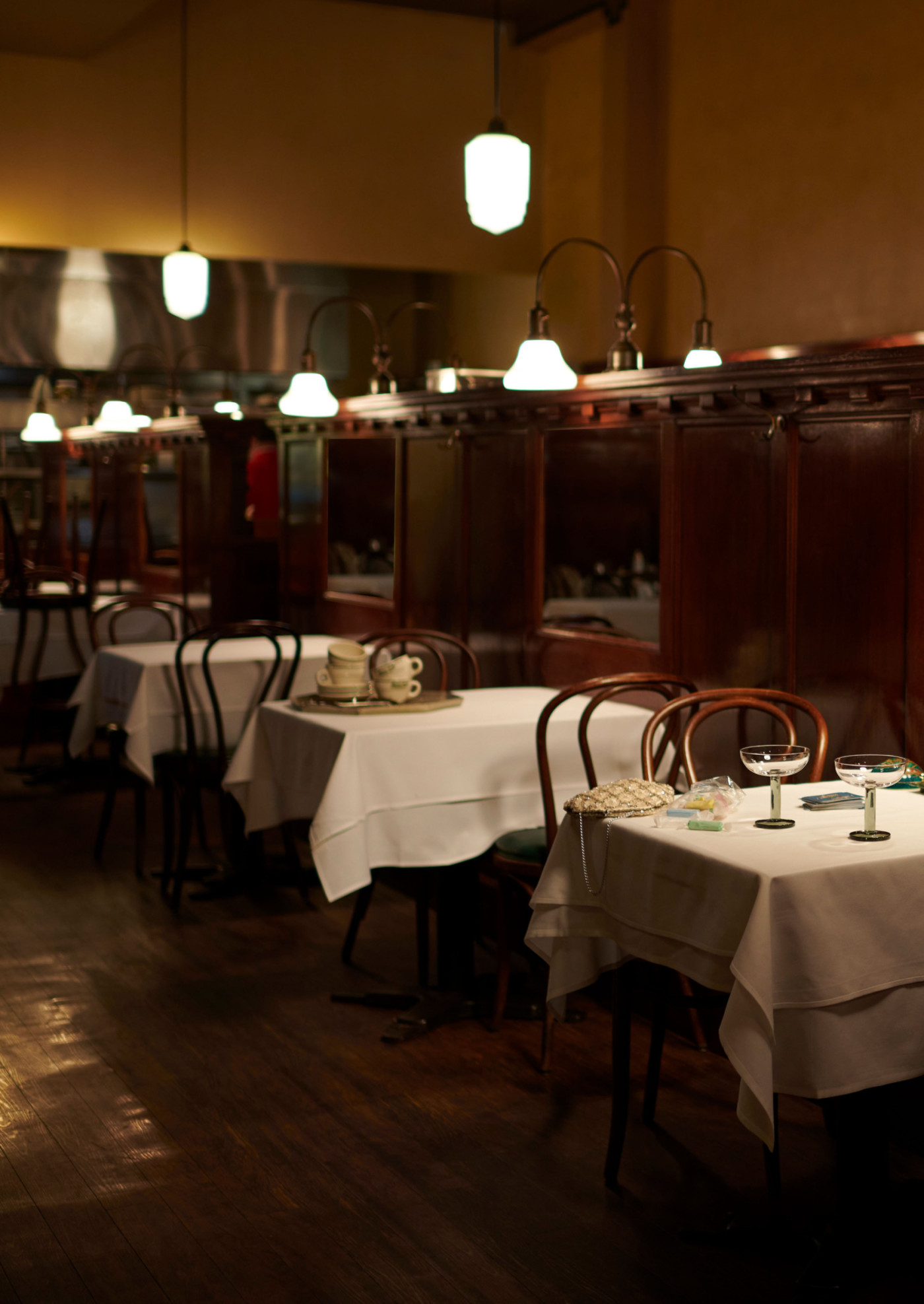 a dimly lit restaurant with tables and white tablecloths.