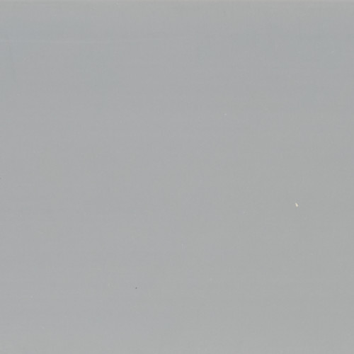 Large smooth matte gray surface with scattered tiny white specks; uniformly lit and stationary; fills frame, suggesting a neutral wall or overcast sky with soft ambient lighting.