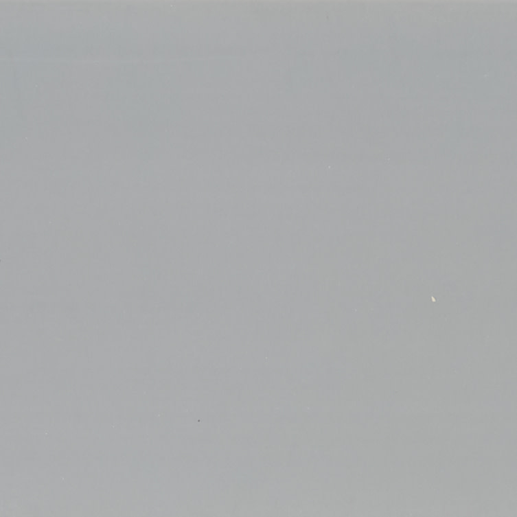 Large smooth matte gray surface with scattered tiny white specks; uniformly lit and stationary; fills frame, suggesting a neutral wall or overcast sky with soft ambient lighting.