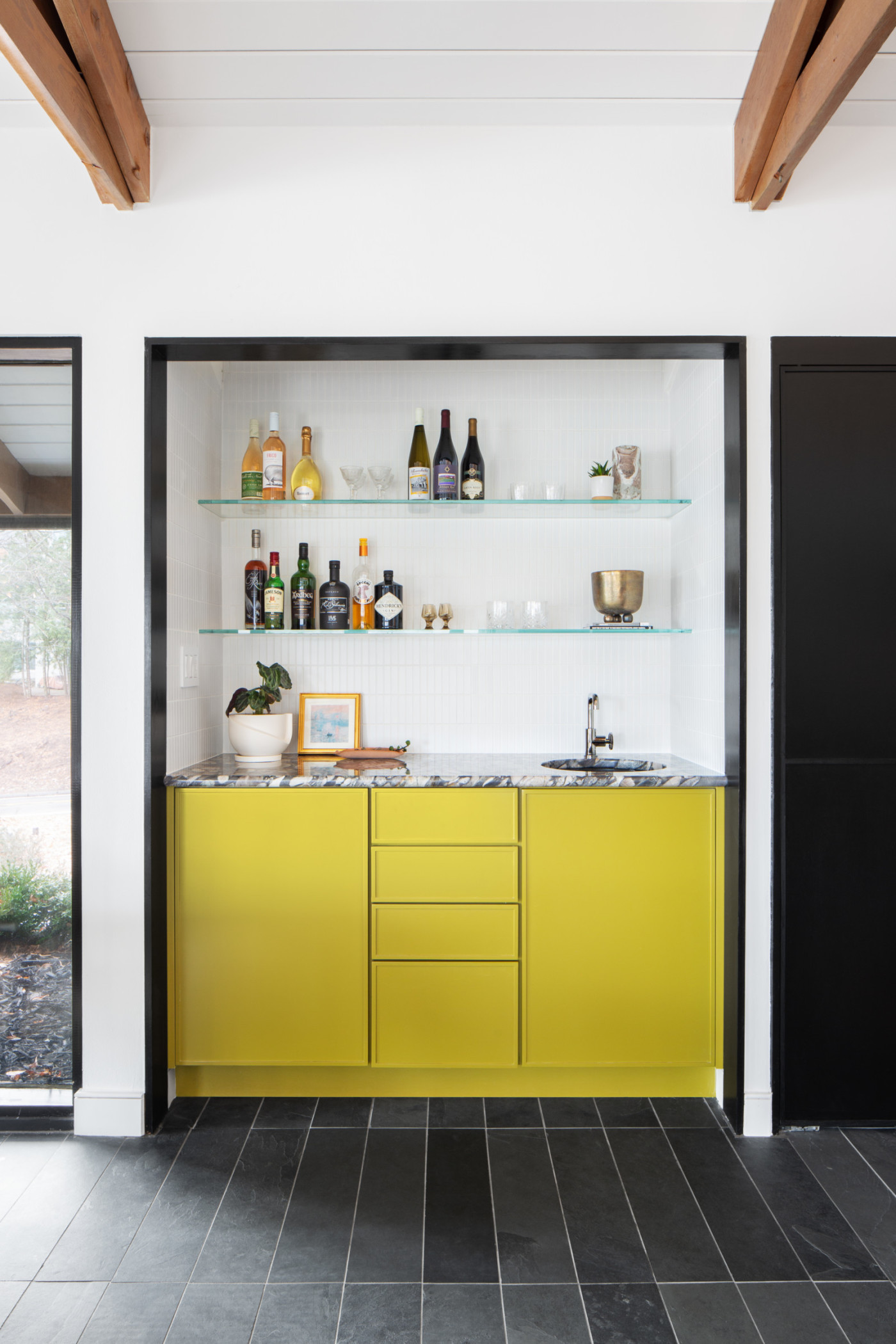 a kitchen with yellow cabinets and a black tile floor.