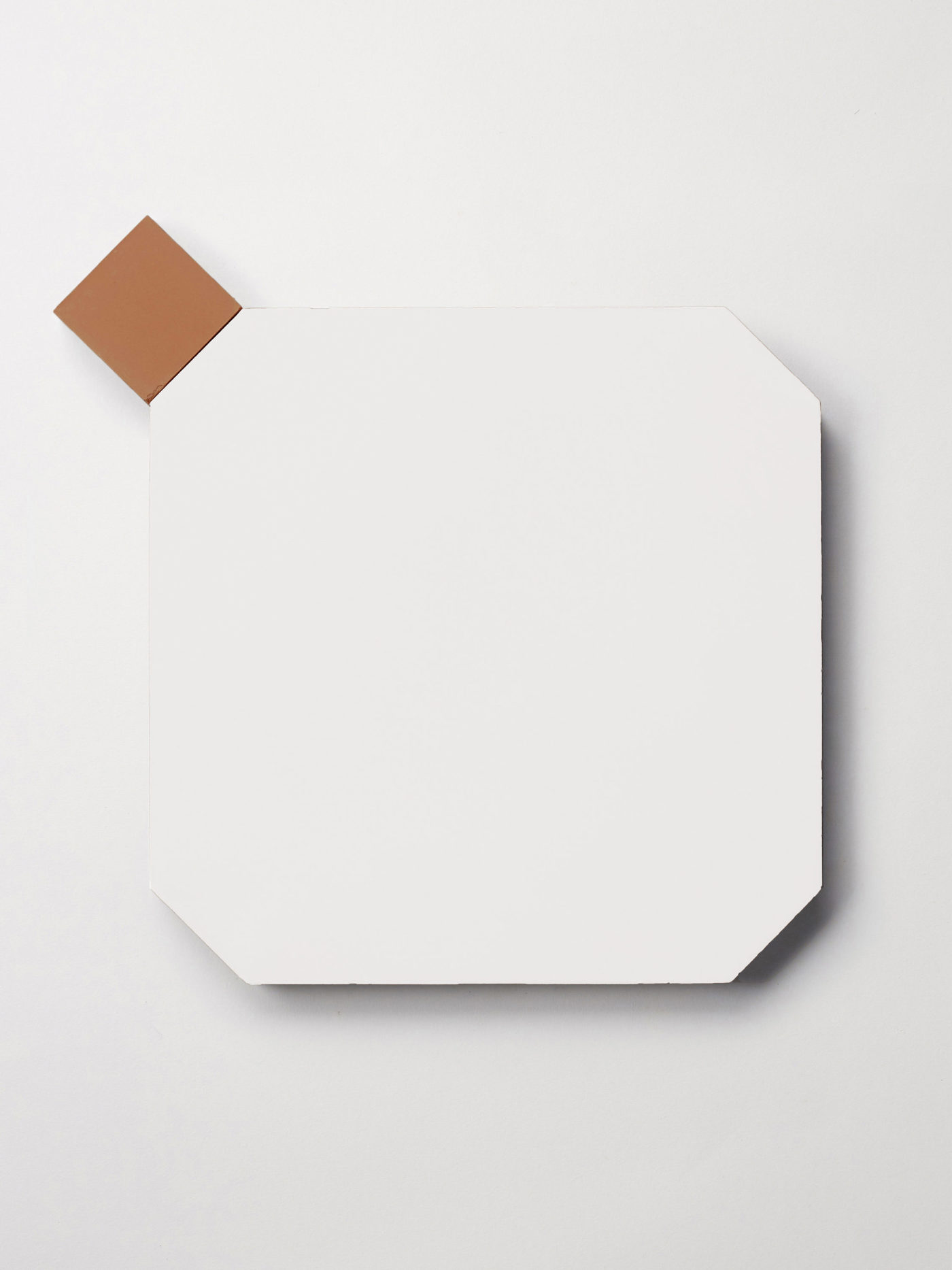 a white tile in the shape of an octagon next to a small red square tile.