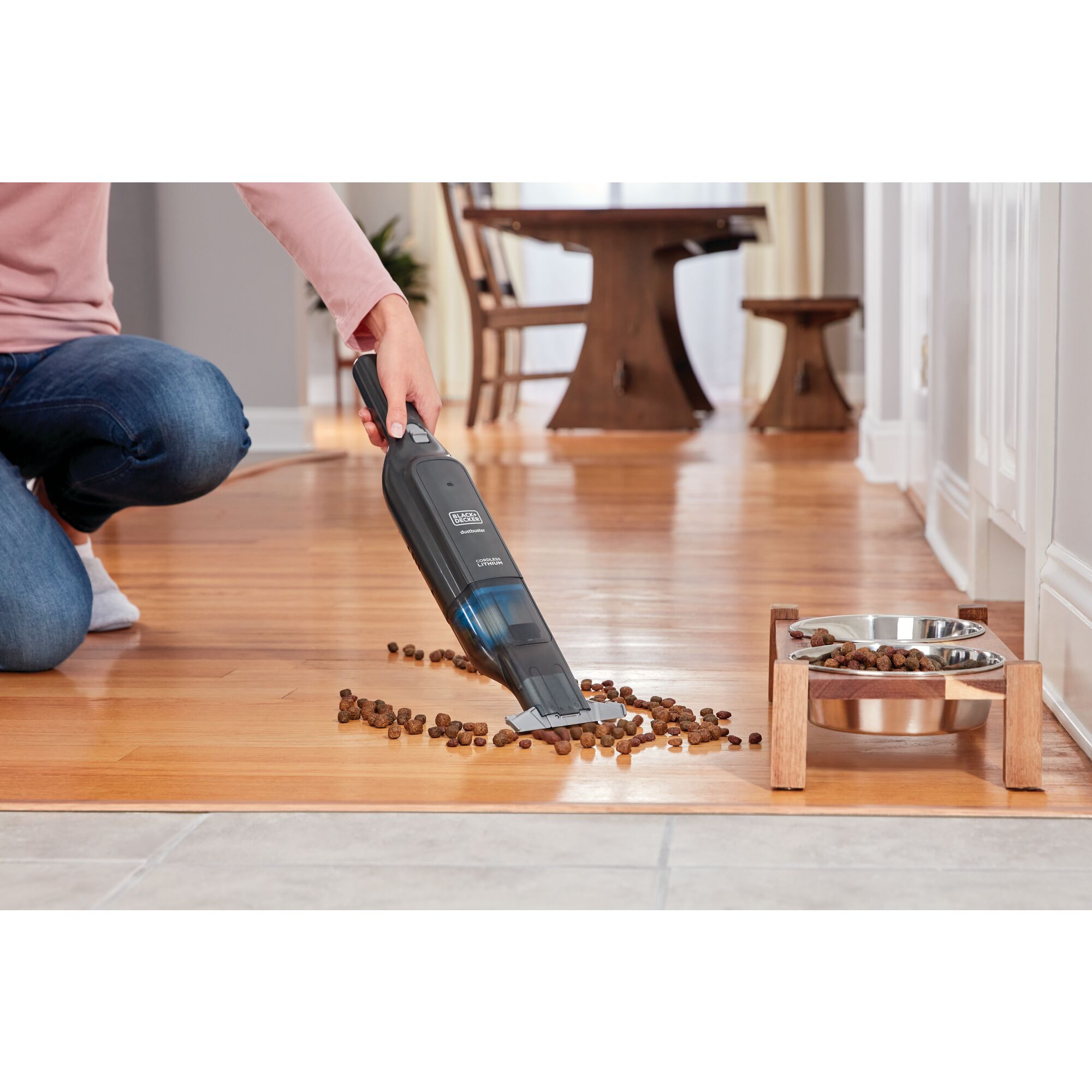 dustbuster Advanced Clean Cordless Hand Vacuum being used to pick up pet food dropped on floor.