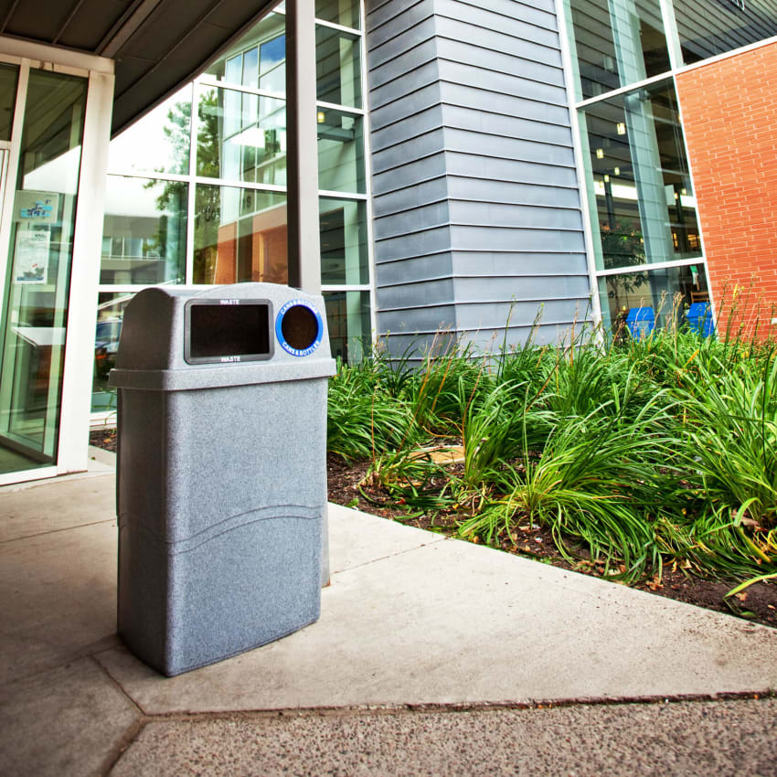 double trash and recyclables collection bin with a canopy lid outside the entrance of a city library