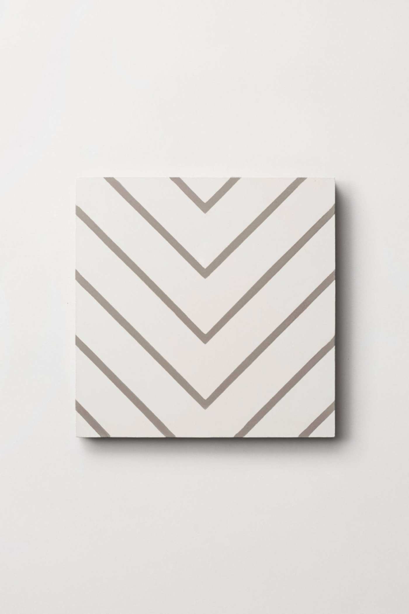 a square tile with a white and grey chevron pattern on a white surface.