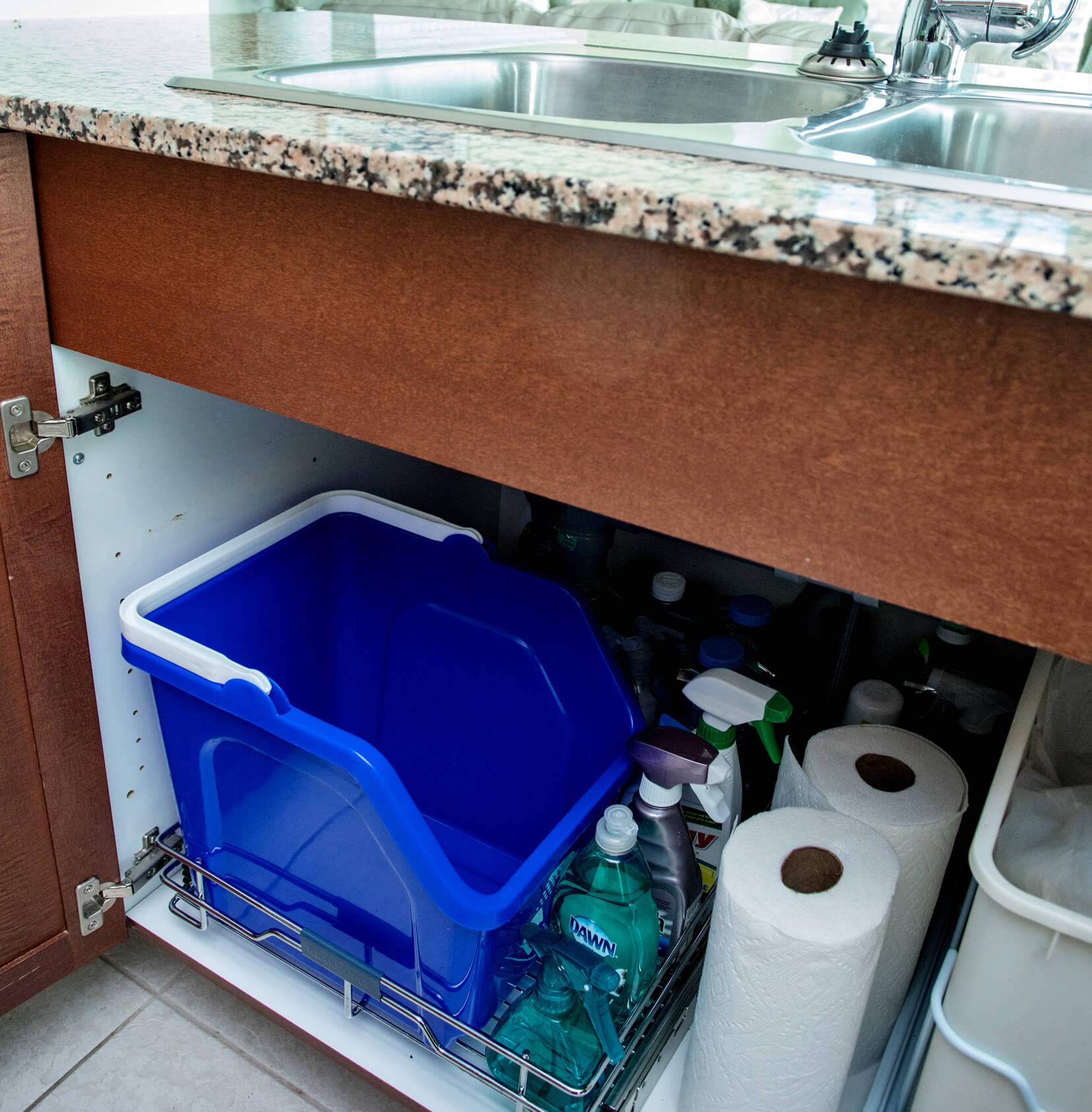blue stackable plastic recycling container with handle for easy transport placed under the kitchen sink for collecting cans and bottles