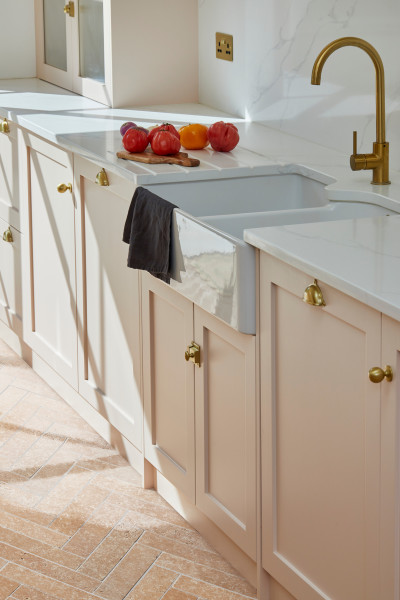 a kitchen with a white sink and brass handles.