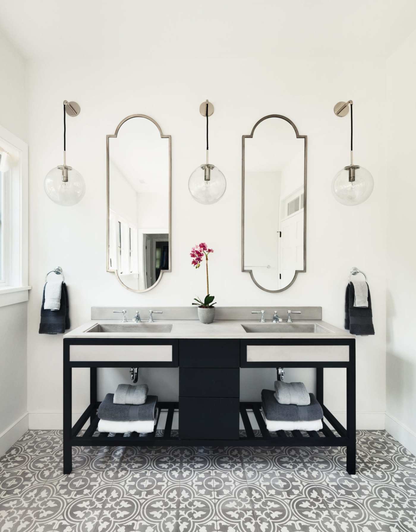 a bathroom with black and white tile and mirrors.