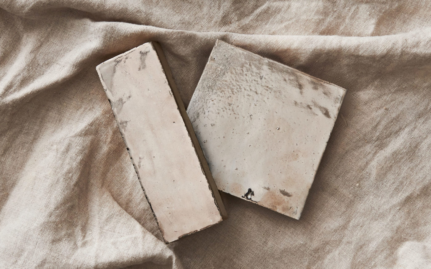 two pieces of tile on a beige cloth.