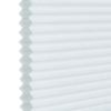 White honeycomb (cellular) blind, hexagonal pleats visible along the left edge; closed and diffusing light; photographed close-up against a neutral background, showing even soft daylight and subtle texture.