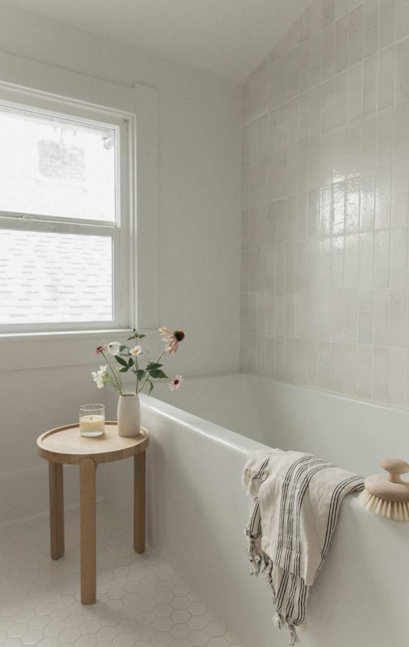 a white bathroom with a tub and a window.