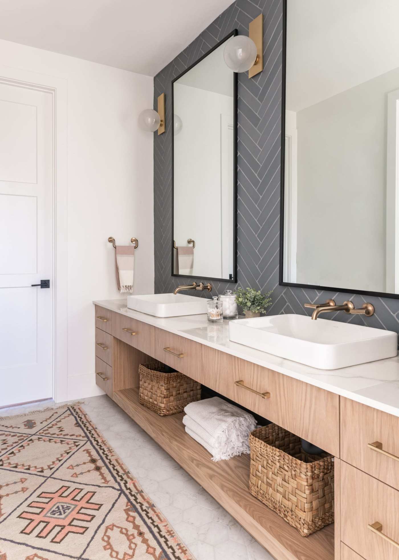 a bathroom with two sinks, a mirror and a rug.