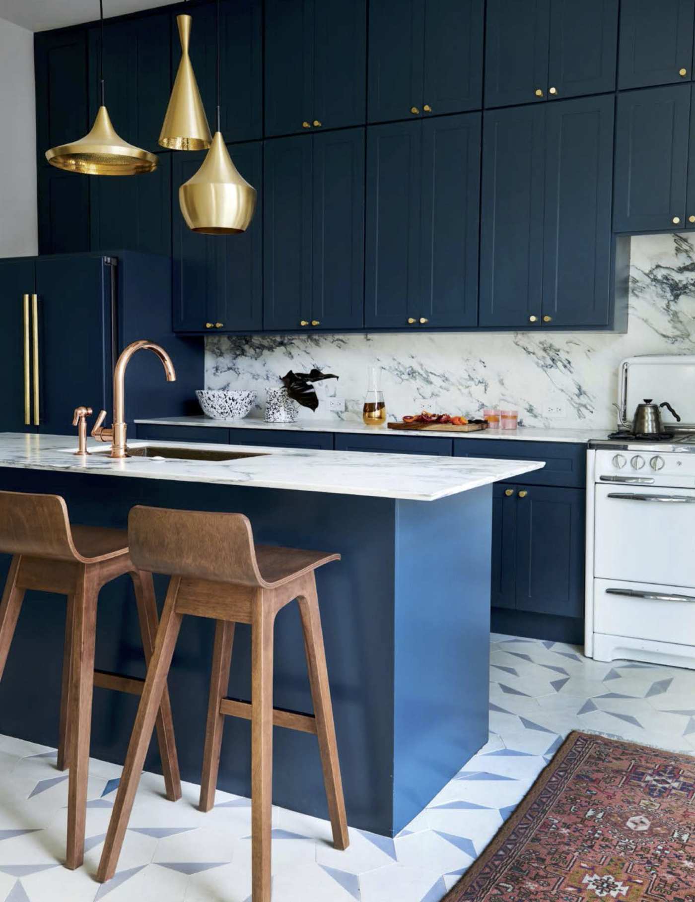 a kitchen with blue cabinets and gold accents.