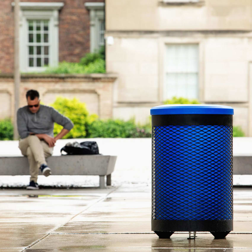 Metal body outdoor recycling bin with plastic blue liner and lid to help improve collection sitting outside a corporate office