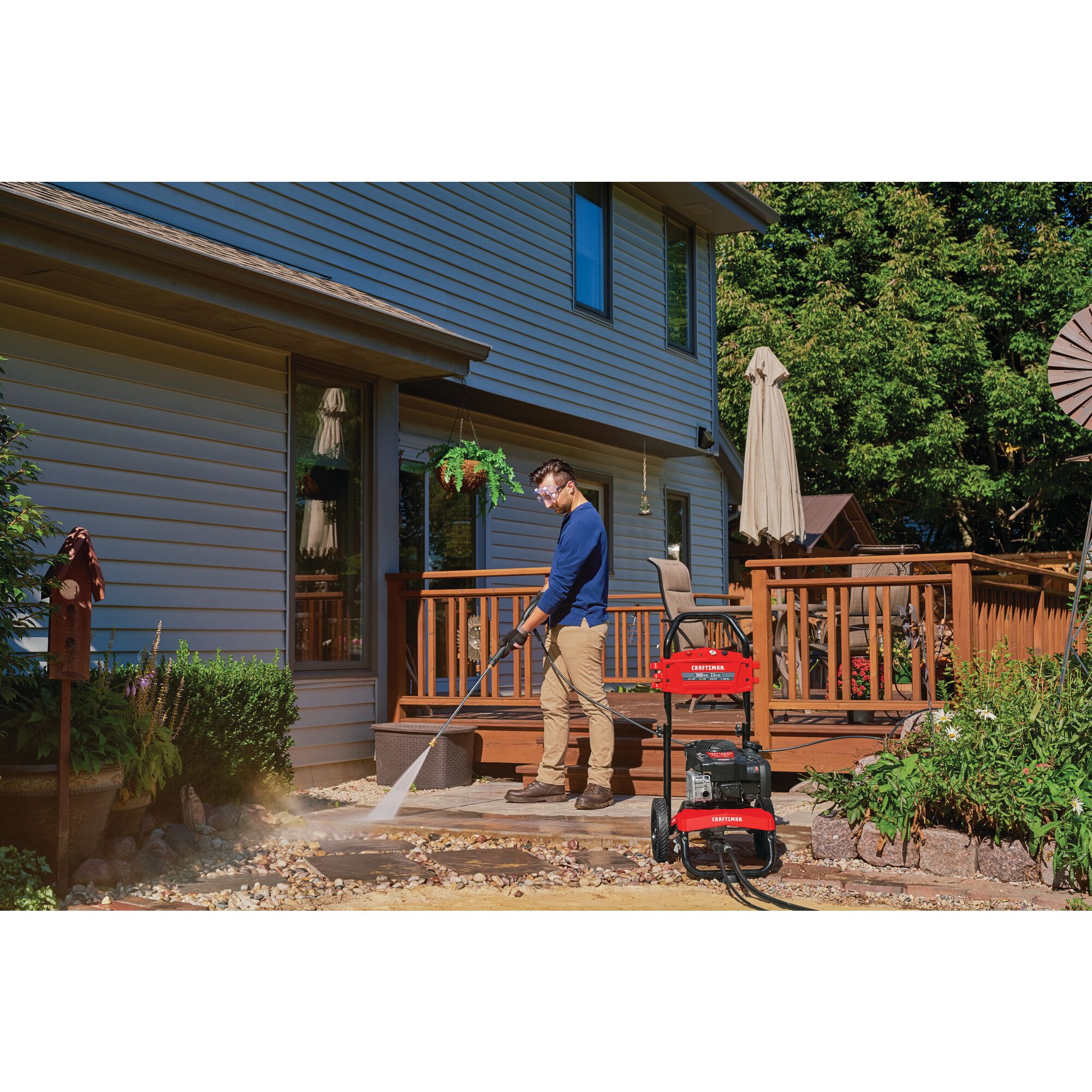 2800 MAX Pounds per Square Inch or 2 and three tenths MAX Gallons Per Minute Pressure Washer being used by person to wash stoned pavement in home garden outdoors.