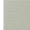 Cream cellular (honeycomb) window blind, fully lowered with visible hexagonal pleats at the left edge; closed and diffusing light; close-up against a plain white background with soft lighting.
