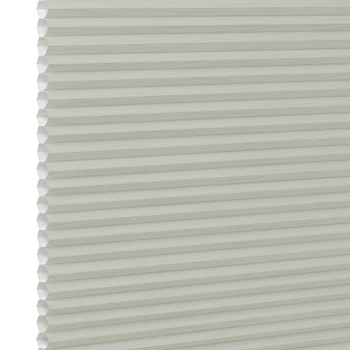 Cream cellular (honeycomb) window blind, fully lowered with visible hexagonal pleats at the left edge; closed and diffusing light; close-up against a plain white background with soft lighting.