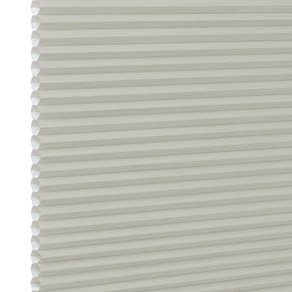 Cream cellular (honeycomb) window blind, fully lowered with visible hexagonal pleats at the left edge; closed and diffusing light; close-up against a plain white background with soft lighting.