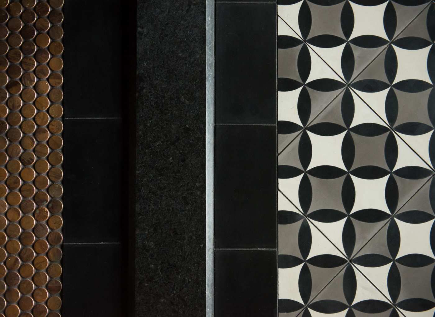 a row of black, white, and grey tiles in a bathroom.